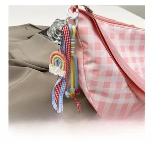 Detail of woven rainbow charm with colorful plaid ribbons and beads on a shoulder bag