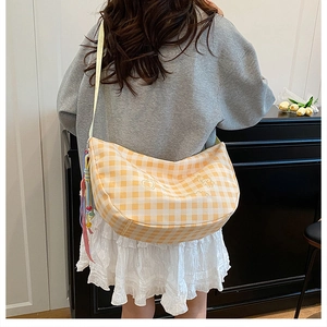 Detail of yellow checkered hobo bag with teddy bear pattern and colorful tassel