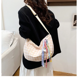 Detail of checkered hobo bag with heart embroidery and colorful rainbow tassel charm