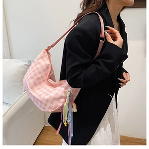 Close-up of pink checkered canvas bag with heart embroidery and rainbow tassel detail