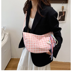 Detail of pink gingham half-moon bag featuring heart embroidery and rainbow charm