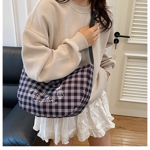 Detail of checkered crossbody bag worn by model in a warm indoor setting