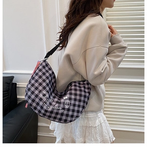 Model wearing a black and grey plaid half-moon bag with cartoon bear and heart patterns