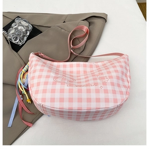 Detail of pink plaid crescent bag featuring bear embroidery and a colorful beaded charm
