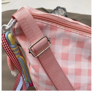 Detail of pink gingham crossbody bag showing adjustable nylon strap and metal buckle