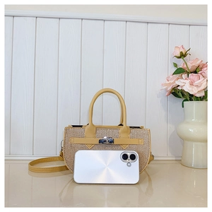 Detail of beige woven crossbody bag showing compact size compared to a smartphone