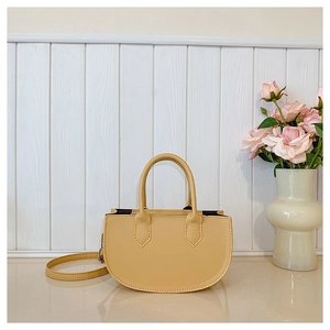 Close-up of semi-circle apricot leather handbag with top handles and rose background