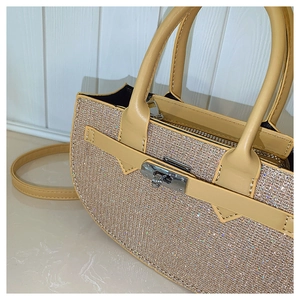 Detailed close-up of champagne rhinestones and metal twist lock on a beige handbag