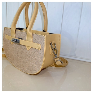 Detail of beige leather handbag with glitter panel and silver twist-lock closure