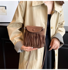 Nahaufnahme einer braunen Wildledertasche mit langen Fransen und schmalem Schultergurt
