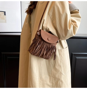 Detail einer braunen Umhängetasche aus Wildleder mit Fransen und Vintage-Schnallen