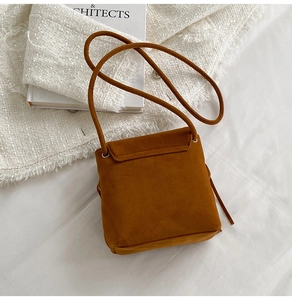 Top view of caramel suede crossbody bag detail with long strap on tweed fabric