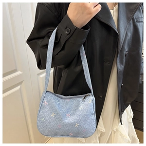 Detail of light blue denim tote bag with colorful bows shown on person's shoulder
