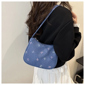 Detail of blue denim shoulder bag featuring pink and white butterfly bow embroidery