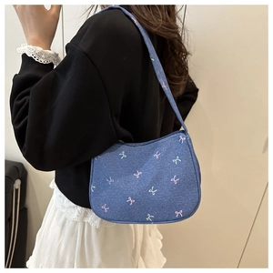 Detail of blue denim underarm bag with colorful butterfly embroidery and bow designs