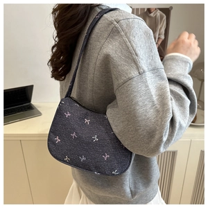 Detail of dark blue denim shoulder bag with colorful ribbon bow embroidery shown on model