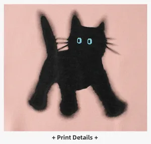 Detailed close-up of fuzzy black cat print with blue eyes on pink fleece sweatshirt