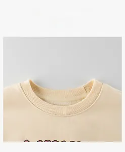 Close-up of ribbed crew neck and fleece texture on a beige children hoodie sweatshirt