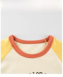 Detail of kids raglan T-shirt showing cream body with yellow sleeves and orange neckline