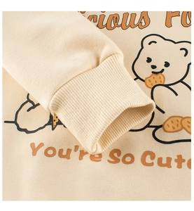 Close-up of ribbed cuffs and cute cartoon bear print on cream long sleeve sweatshirt