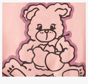 Détail du sweat-shirt en maille rose avec un motif d'ours mignon sur le tissu doux