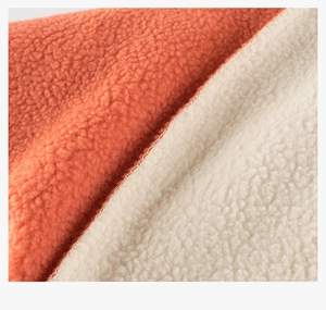 Detail of soft orange and beige sherpa fleece fabric with neat overlock stitching