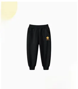Dettaglio dei pantaloni sportivi neri per bambini con stampa smiley arancione e vita a coste