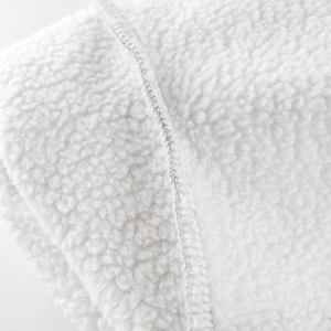 Détail macro de la texture polaire sherpa blanche douce avec bordure cousue de qualité