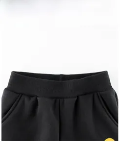 Dettaglio ravvicinato dell'elastico in vita a coste e tasche dei pantaloni neri da bimbo
