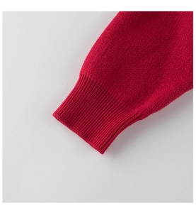 Close-up of bright red knit sweater sleeve showing fine texture and ribbed cuffs