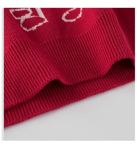 Detailed close-up of red knit sweater hem featuring ribbed cuffs and white woven patterns
