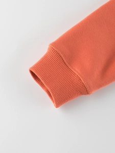 Detail of high-density orange cotton ribbed cuffs on a long-sleeved children's sweatshirt