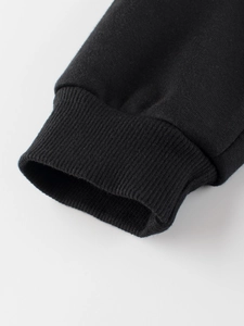 Dettaglio del polsino elastico a costine su pantaloni sportivi neri per bambine