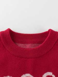 Close-up of red knit sweater with round ribbed neckline and white jacquard pattern