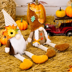 Close-up of plush harvest gnomes with long legs and striped hats on a cozy autumn backdrop