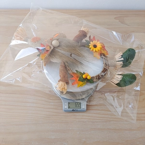 Close-up of harvest gnome wreath with burlap hat and autumn maple leaves on scale