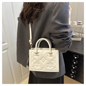 Close-up of the white square bag featuring intricate floral embossing and gold hardware