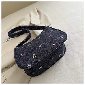 Detailed close-up of dark denim shoulder bag with colorful bow embroidery patterns