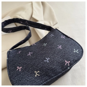 Macro detail of blue denim shoulder bag with colorful bow prints on crescent moon shape