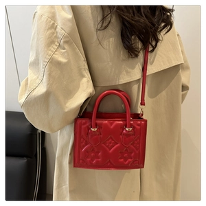 Detail of red embossed small square bag with star patterns on beige trench coat