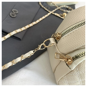 Detail of off-white leather crossbody bag with lychee texture and gold chain strap
