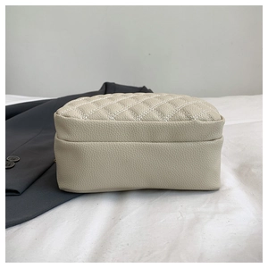 Close-up of beige quilted leather texture and fine stitching on the stylish shoulder bag