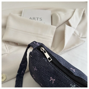 Detail of dark denim underarm bag with colorful bow prints and metal zipper