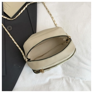 Detail of beige pebble leather round bag showing spacious interior and double zippers