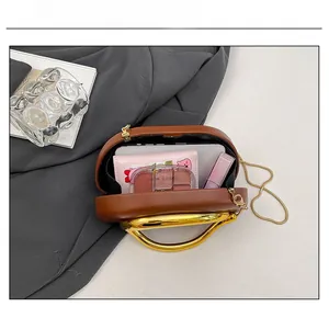 Bovenaanzicht van de bruine clutch met goudkleurig handvat en interne capaciteit