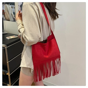 Detail of red faux suede tote bag with long dense fringe tassels and shoulder strap