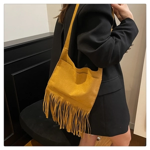 Detail of yellow suede shoulder bag featuring long fringe tassels and vintage design