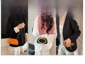 Detail van de clutch in drie kleuren met gouden U-handvat en schouderketting