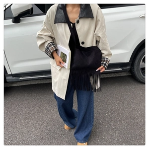 Detail of vintage black crossbody bag with long tassels paired with casual chic outfit