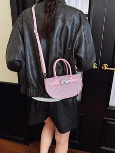 Pink glitter semi-round handbag with silver clasp shown on a model in black leather jacket